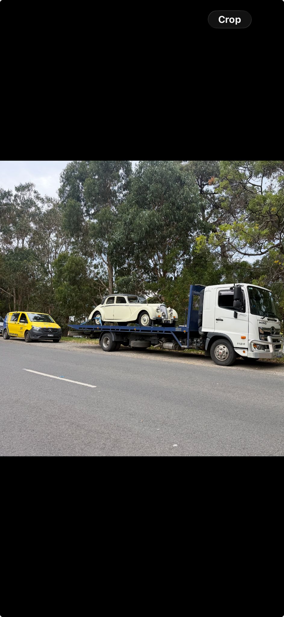 Flatbed truck towing a classic vehicle